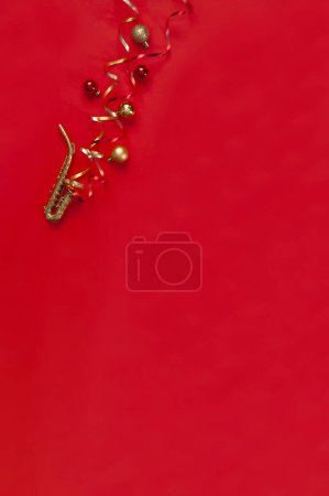 Téléchargez les photos : Fête de Noël rouge et fond du Nouvel An avec Miniature copie de saxophone doré et décor de Noël. Vue du dessus, espace de copie, plan - en image libre de droit