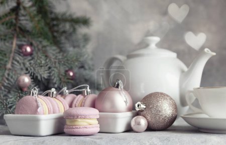 Foto de Composición navideña con galletas macarrones macaroon, bolas de Navidad y set de té en rosa - Imagen libre de derechos