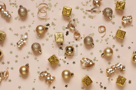 Photo for Festive Christmas New Year golden colored celebration decorations gift boxes, Christmas balls, streamers serpentine and glitter confetti on the Peach Fuzz Color of the year 2024 background - Royalty Free Image