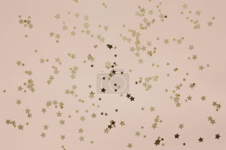 Photo for Festive Christmas New Year golden colored star shape glitter confetti on the Peach Fuzz Color of the year 2024 background - Royalty Free Image