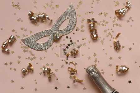 Photo for Festive background with Champagne bottle, carnival mask, streamers serpentine and golden glitter confetti in Peach Fuzz Color of the year 2024 - Royalty Free Image