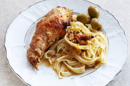 Photo for Baked peace of rabbit meat with tagliatelle pasta, sauce and olives. - Royalty Free Image