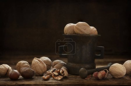 Photo for Walnuts in the metal antique mortar. Artistic Still life in vintage style - Royalty Free Image