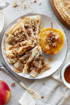 Foto de Deliciosos panqueques caseros, buñuelos con manzana caramelizada, miel y nueces, fondo, vista superior - Imagen libre de derechos