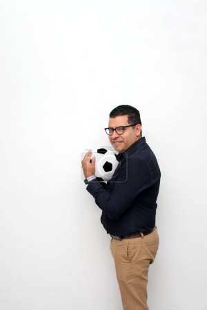 Photo for Latino adult office man plays with a soccer ball very excited that he is going to see the game and wants to see his team win - Royalty Free Image