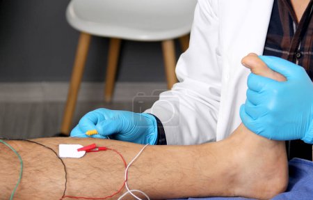 Photo for Electromyography in the lower limbs, graphic recording technique of the electrical activity produced by the tibial muscle performed by a specialist neurologist - Royalty Free Image