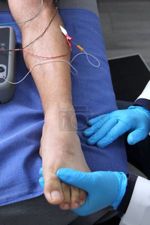 Photo for Electromyography in the lower limbs, graphic recording technique of the electrical activity produced by the tibial muscle performed by a specialist neurologist - Royalty Free Image