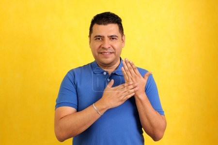 Foto de Hombre adulto latino moreno utiliza lenguaje de señas típico de las personas sordas para establecer un canal de comunicación con su entorno social - Imagen libre de derechos