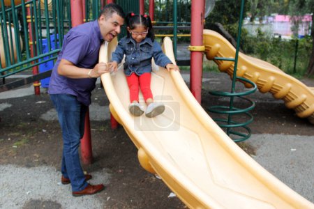 Divorced single dad and 4-year-old daughter Latino brunettes play on outdoor park playground spend quality time together tech-free
