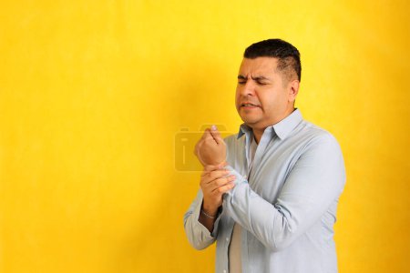 Foto de Hombre latino de 40 años de pelo oscuro sufre de dolor, entumecimiento y hormigueo en la muñeca, la mano y los dedos síntomas del síndrome del túnel carpiano - Imagen libre de derechos