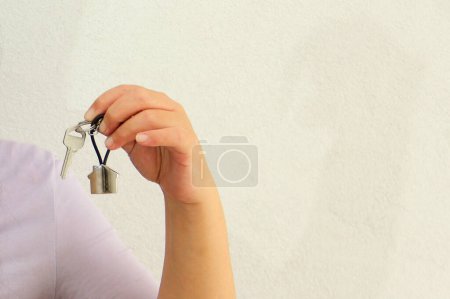 Photo for Latin adult woman shows the keys to her new home on a house-shaped keychain, feels successful and proud of her achievement - Royalty Free Image