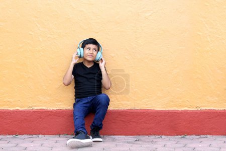Téléchargez les photos : Brown Latino garçon de 9 ans avec casque anti-bruit pour les enfants atteints du syndrome d'asperger, du trouble du spectre autistique, du TDAH et les enfants sensibles aux bruits forts - en image libre de droit