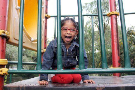 Photo for 4 year old Latina brunette girl with eye glasses plays in the playground as therapy for Attention Deficit Hyperactivity Disorder ADHD - Royalty Free Image