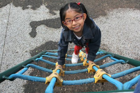 Chica morena latina de 4 años con anteojos juega en el patio como terapia para el Trastorno por Déficit de Atención con Hiperactividad TDAH