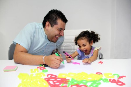 Téléchargez les photos : Divorcé père célibataire avec sa fille brune Latino cheveux bouclés faire des devoirs, jouer, s'amuser et passer du temps de qualité - en image libre de droit
