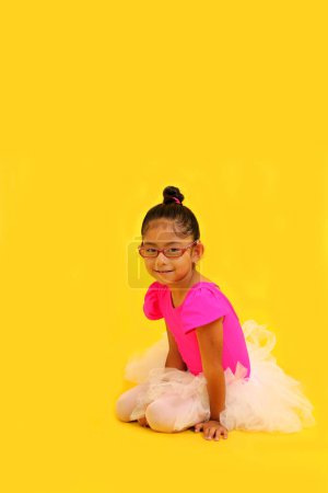 Photo for 4-year-old brunette Latina girl with eyeglasses dressed in pink leotard and ballerina tutu takes ballet classes as therapy for her autism and ADHD - Royalty Free Image