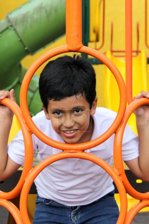 Photo for 9-year-old dark-skinned Latino boy plays in a playground as a physical activity living in poverty as therapy for ADHD - Royalty Free Image