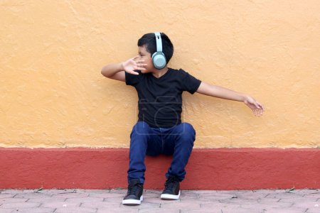 Foto de Niño latino de piel oscura de 9 años utiliza audífonos que alteran el aprendizaje, la memoria y la capacidad de retención, produciendo aislamiento social, hipocausia y tinnitus. - Imagen libre de derechos