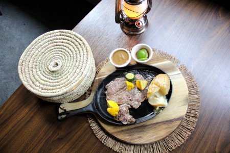 Carne asada acompañada de pimientos y papas al horno con tortillas, frijoles y limones al estilo mexicano