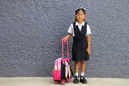 4 ans Latina fille brune avec des lunettes, uniforme et sac à dos marche à l'école ce retour à l'école