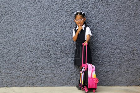 Foto de Chica morena latina de 4 años con anteojos, uniforme y mochila camina a la escuela esto de regreso a la escuela - Imagen libre de derechos
