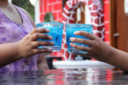 Téléchargez les photos : Deux jeunes femmes latines de 20 ans boivent un cocktail bleu givré au chili, célèbrent en buvant de l'alcool - en image libre de droit