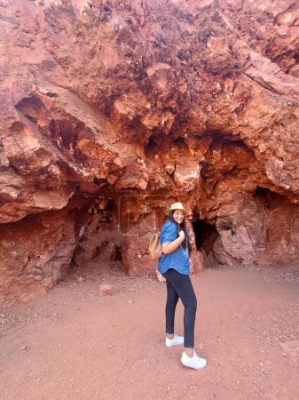 Latin adult woman geologist with hat explores and investigates opal mine, studies the minerals and analyzes the red land