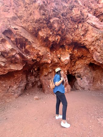 Geóloga latina adulta con sombrero explora e investiga mina de ópalo, estudia los minerales y analiza la tierra roja