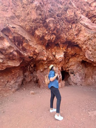 Latin adult woman geologist with hat explores and investigates opal mine, studies the minerals and analyzes the red land