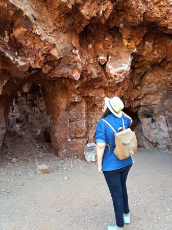 Lateinische erwachsene Geologin mit Hut erforscht und erforscht das Opalbergwerk, untersucht die Mineralien und analysiert das rote Land