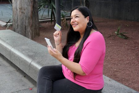 40-jährige Latina nutzt Handy und Kreditkarte, um zu bezahlen, online zu kaufen, Angebote und Rabatte im Internet zu nutzen
