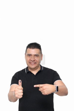 Dark-skinned Latino adult man shows his inked thumb after exercising his free and secret vote in Mexico