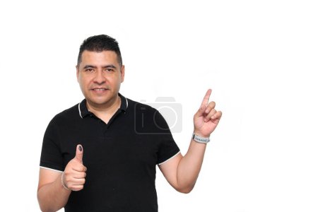 Hombre adulto latino de piel oscura muestra su pulgar entintado después de ejercer su voto libre y secreto en México