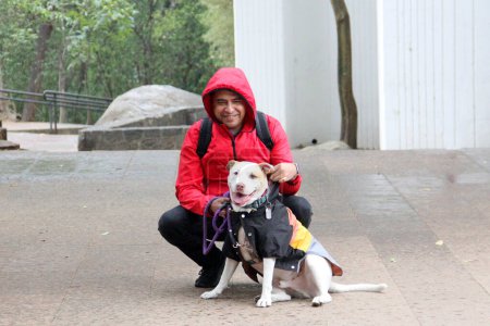 Divorcé célibataire dans la quarantaine latino à la peau foncée se prépare à marcher sous la pluie dans le parc avec son chien de soutien émotionnel