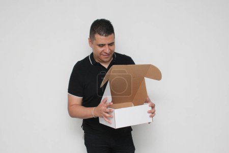 Hombre adulto latino ensambla una caja de cartón siguiendo las instrucciones para lograrlo