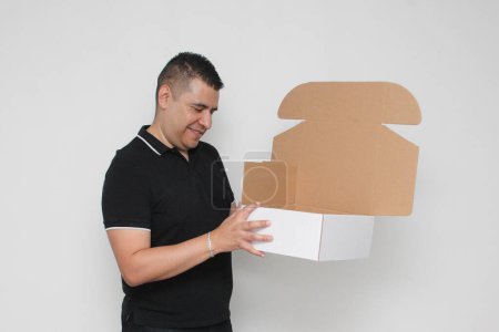 Latino homme adulte assemble une boîte en carton en suivant les instructions pour y parvenir