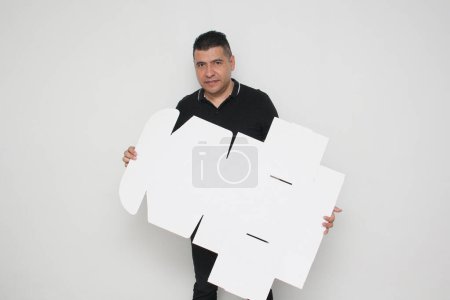 Ein erwachsener Mann aus Lateinamerika baut einen Karton zusammen, der den Anweisungen folgt, um ihn zu erreichen