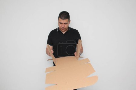 Latino homme adulte assemble une boîte en carton en suivant les instructions pour y parvenir
