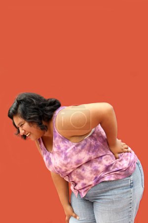 Junge brünette Latino-Frau von 20 Jahren leidet unter Rücken-, Wirbelsäulen- und Nackenschmerzen aufgrund von Verspannungen und schlechter Körperhaltung