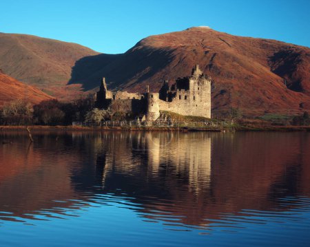 Scottish ruins of an ancient castle on an autumn morning. Autumn colours in the hills behind. Kilchurn Castle, Loch Awe, Argyll and Bute, Scotland, UK