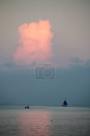 A traditional boat sails on a calm sea in the morning.