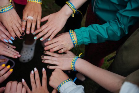 Téléchargez les photos : Les mains d'un groupe d'enfants. Les gens ensemble dans des bracelets bleus et jaunes de rubans couleur du drapeau ukrainien. Amitié, unité, soutien. Esprit de liberté et de lutte. Gloire à l'Ukraine! - en image libre de droit