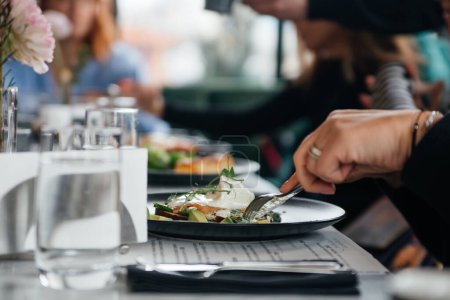 Téléchargez les photos : Femme manger un sandwich à l'avocat et au saumon dans un restaurant - en image libre de droit