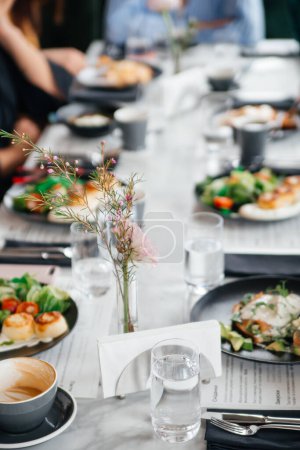 Téléchargez les photos : Table de restaurant avec divers plats, tasse de café, verres d'eau et champagne rose - en image libre de droit