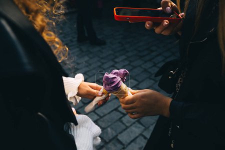 Téléchargez les photos : Jeunes femmes tenant des cônes avec de la crème glacée pourpre et prenant des photos avec smartphone - en image libre de droit