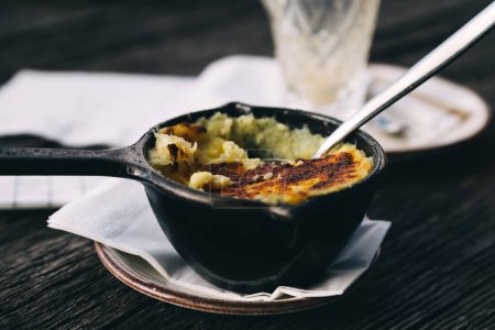 Téléchargez les photos : Purée de pommes de terre cuites au four avec une croûte dans une casserole noire - en image libre de droit