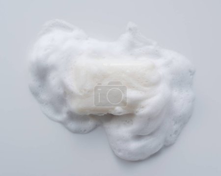 Solid soap with foam placed on white background. Viewed from directly above.