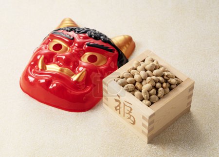 Foto de Beans for bean-throwing and masks of ogres placed on a Japanese-style golden background. Japanese ogres. Setsubun image. - Imagen libre de derechos