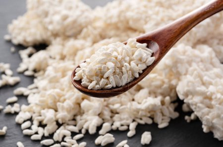 Foto de Closeup of rice koji and wooden spoon placed on black background. Koji. Koji is fermented rice. - Imagen libre de derechos