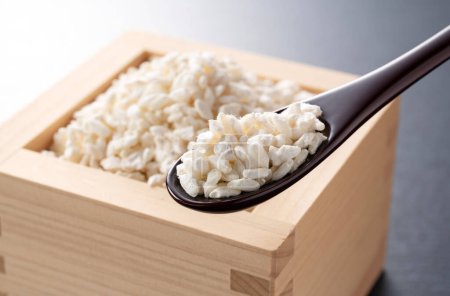 Photo for Rice koji in a box and a wooden spoon placed against a black background. Koji. Koji is fermented rice. - Royalty Free Image